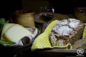 Mesa com pão rústico, queijo e vinho tinto num restaurante no Talasnal