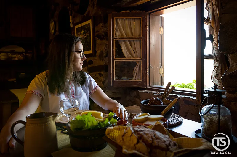 Interior rústico de restaurante no Talasnal com mesa tradicional junto à janela