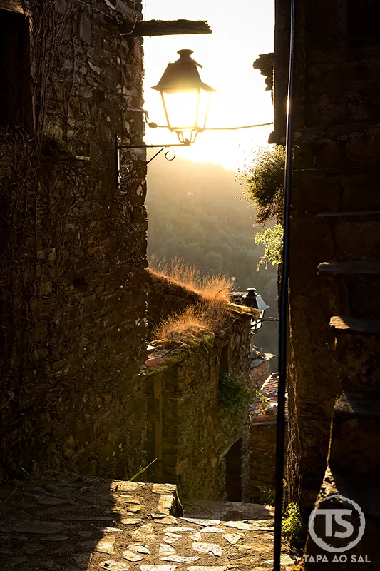 Beco de xisto no Talasnal ao pôr do sol com candeeiro antigo