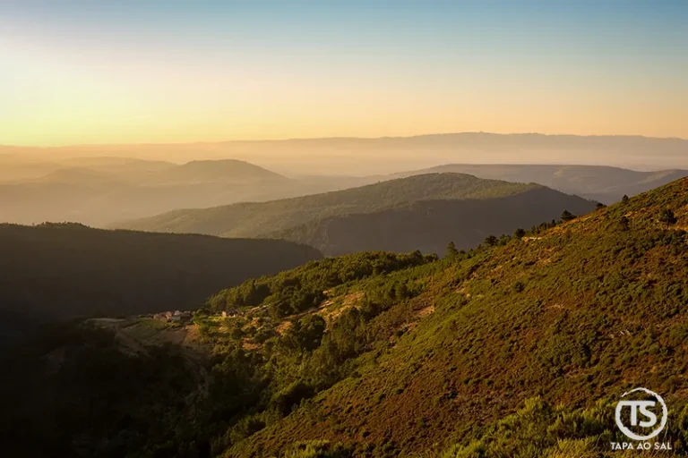 Paisagem ampla da Serra da Lousã ao entardecer, com encostas e vales em camadas