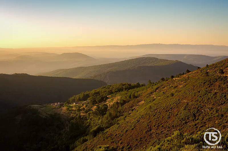Paisagem ampla da Serra da Lousã ao entardecer, com encostas e vales em camadas