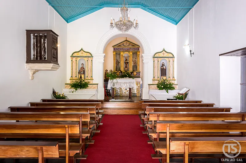 Interior do Santuário de Nossa Senhora da Piedade, na Lousã, com vista para o altar principal, bancos de madeira e teto pintado em azul.