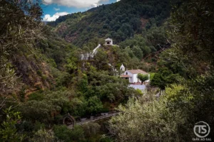 Vista panorâmica do Santuário de Nossa Senhora da Piedade, na Lousã, rodeado pela vegetação da serra e encaixado num vale verdejante.
