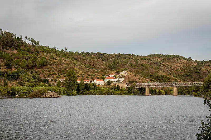 Vista da ponte de Belver sobre o Tejo, com a aldeia e colinas ao fundo, no início do passadiço do Alamal