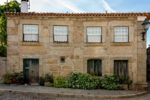 Casa tradicional em granito na zona histórica de Santar, com janelas alinhadas e vasos de flores à porta.