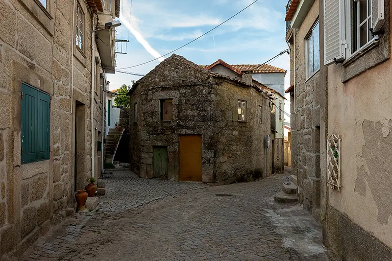 Rua em calçada de granito na zona histórica de Santar, com casas tradicionais de pedra.