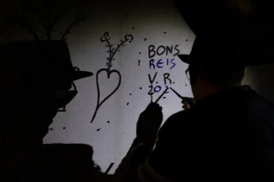 Reiseiro a pintar símbolos na fachada de uma casa durante a tradição dos Reis em Alenquer