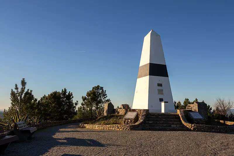 Marco Geodésico do Centro de Portugal no Picoto da Melriça ao final da tarde, com céu dourado e vista para a paisagem montanhosa ao redor.