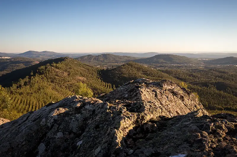 Vista panorâmica da paisagem ao redor do Centro Geodésico de Portugal em Vila de Rei, com montanhas, campos verdes e céu aberto.