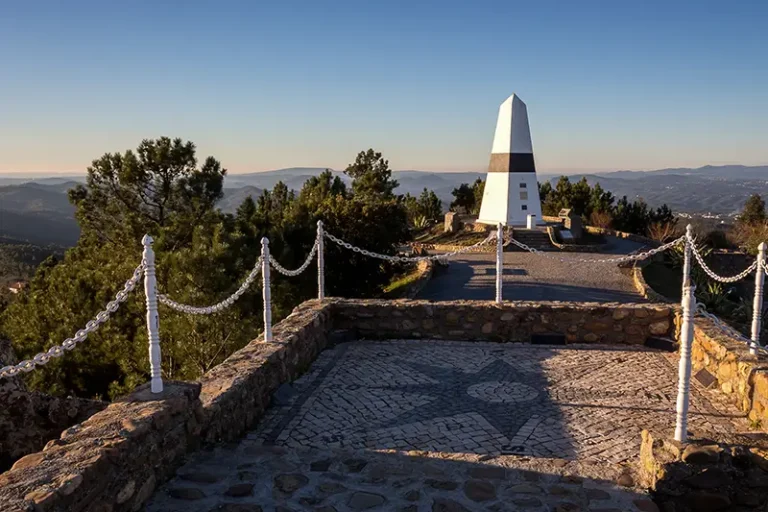 Imagem do Centro Geodésico de Portugal no Picoto da Melriça, em Vila de Rei, com vista panorâmica da paisagem ao redor, incluindo a Serra da Lousã e a Serra da Estrela ao fundo, representando o ponto central do país.