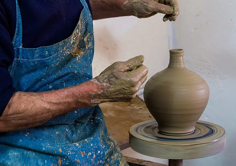 Oleiro a moldar barro num torno de olaria, em processo tradicional de artesanato português.