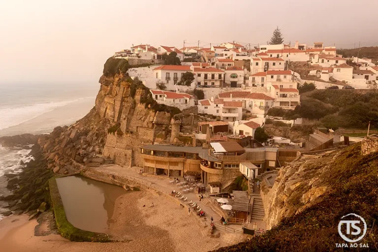 Casas brancas nas falésias e piscina natural em Azenhas do Mar ao entardecer