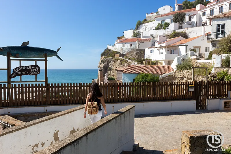 Turista a caminho do miradouro das Azenhas do Mar com vista sobre as casas na falésia.