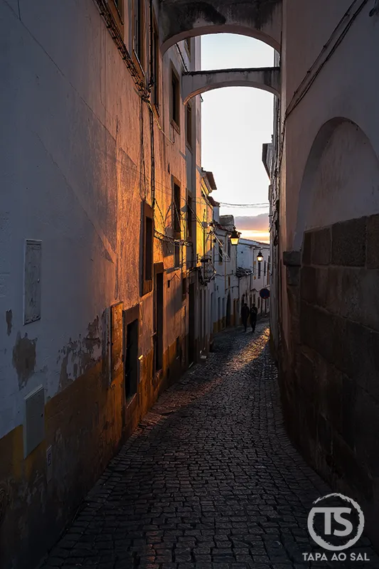 Rua estreita do centro histórico de Évora ao entardecer com luz dourada nas fachadas