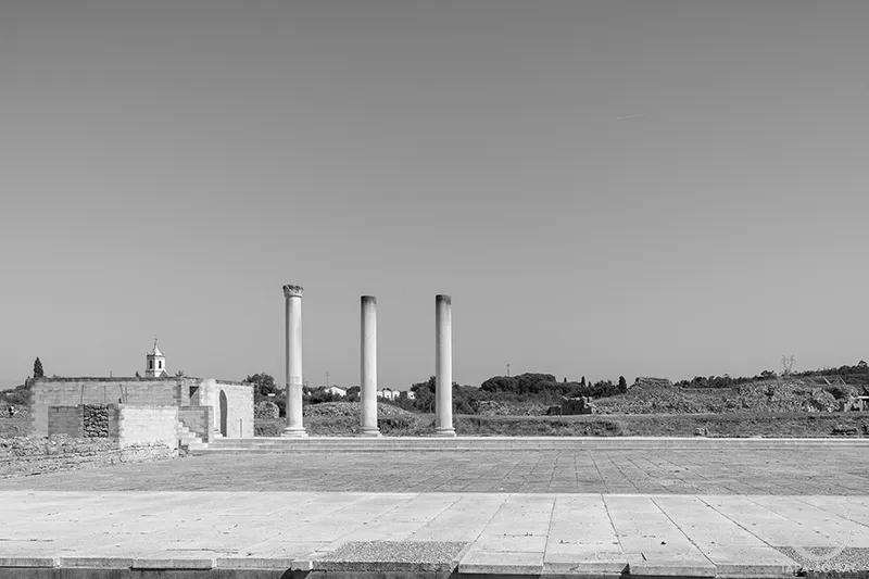 Colunas do fórum romano nas Ruínas de Conímbriga, em Portugal, com paisagem ao fundo.