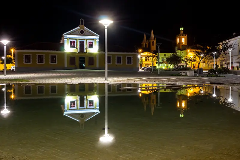 Praça da República em Nisa à noite, com os edifícios históricos refletidos na água – um dos lugares imperdíveis para quem procura nisa o que visitar.