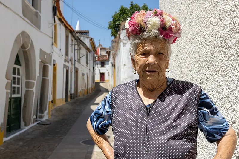 Senhora com coroa de flores nas ruas de Nisa durante as celebrações de São João – tradição viva que enriquece a experiência de quem procura saber nisa o que visitar.