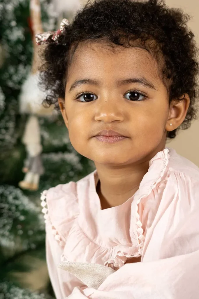 criança em frente à árvore de Natal com vestido rosa