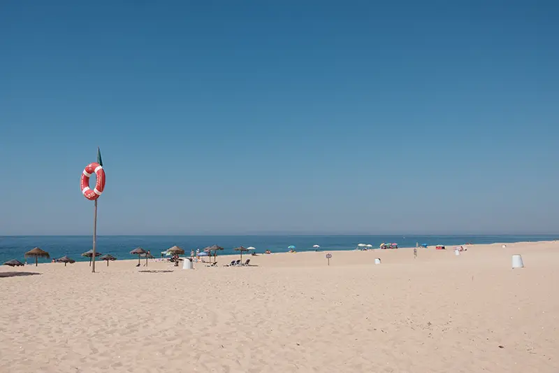 Praia da Costa de Santo André com mar calmo e céu limpo, refletindo a tranquilidade de um dia claro.