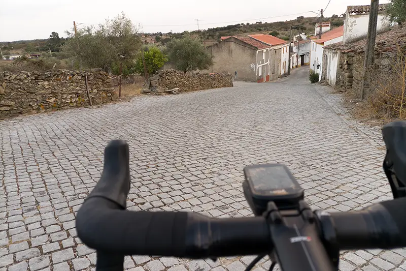 Entrada da aldeia de Velada com estrada de calçada e muros de pedra ao fundo, vindo do Monte do Arneiro.