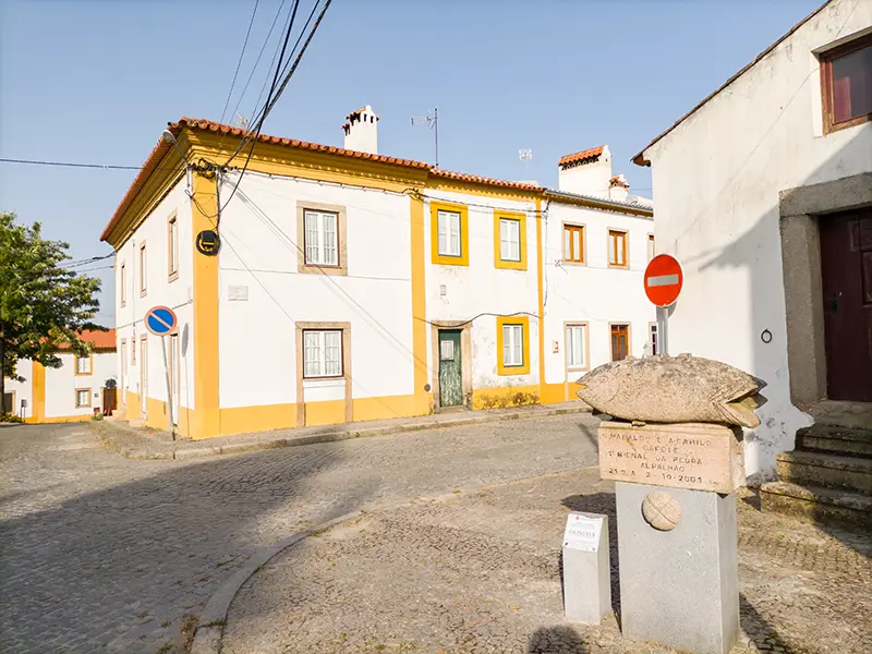 Rua típica de Alpalhão com placa escultórica e casas alentejanas ao fundo – Alpalhão o que visitar