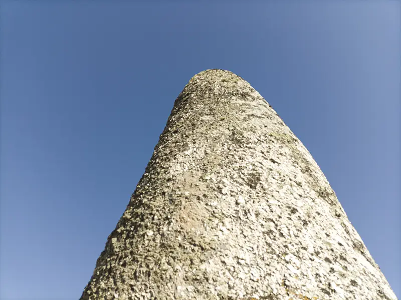 Detalhe da superfície do Menir da Meada visto de baixo, com céu azul limpo ao fundo