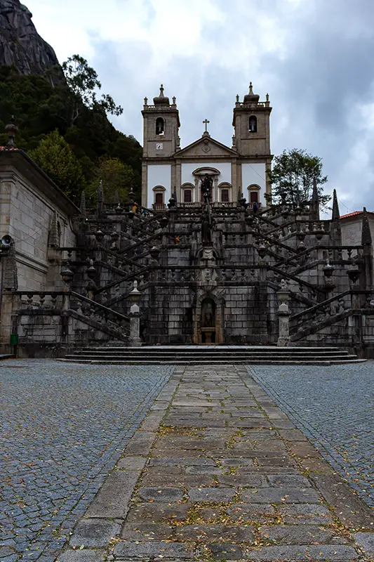 Escadório monumental do Santuário de Nossa Senhora da Penha, em Guimarães, erguendo-se em granito sob céu cinzento — paragem marcante num roteiro rápido para quem procura o que visitar em Portugal.