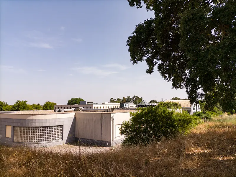 Vista lateral do edifício moderno das Termas da Fadagosa de Nisa, rodeado por vegetação e árvores no Alto Alentejo.