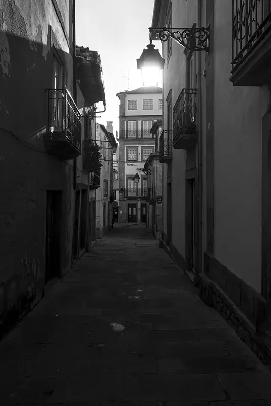 Rua estreita e histórica em Viana do Castelo ao entardecer, com varandas antigas e candeeiro aceso — um dos recantos urbanos a descobrir ao visitar Portugal.
