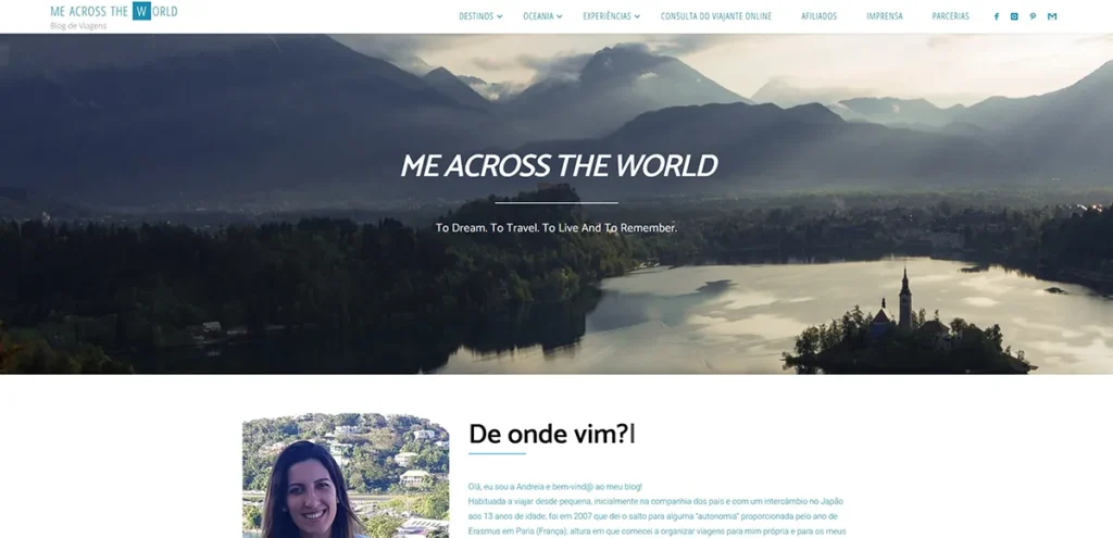 Captura de ecrã da página inicial do blog Me Across The World, com vista panorâmica para um lago e montanhas ao fundo.