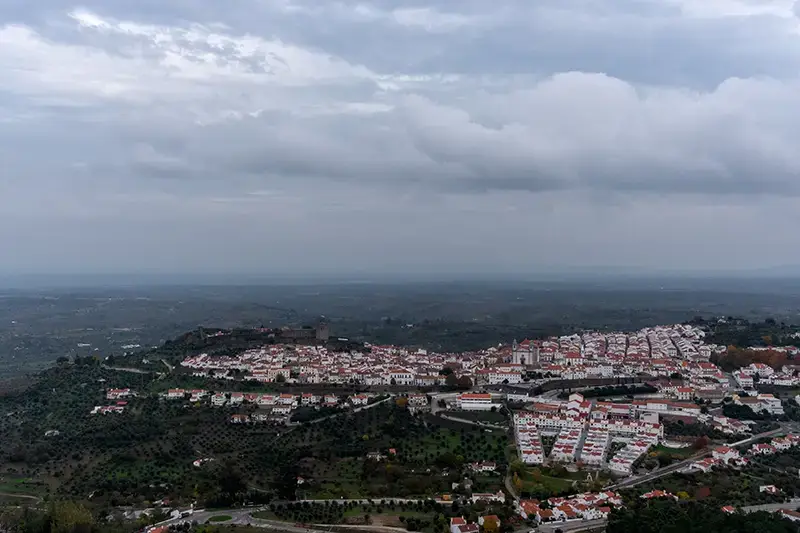 Vista panorâmica de Castelo de Vide com o castelo no topo e as casas brancas espalhadas pela encosta.  📝 Legenda visível (se aplicável):