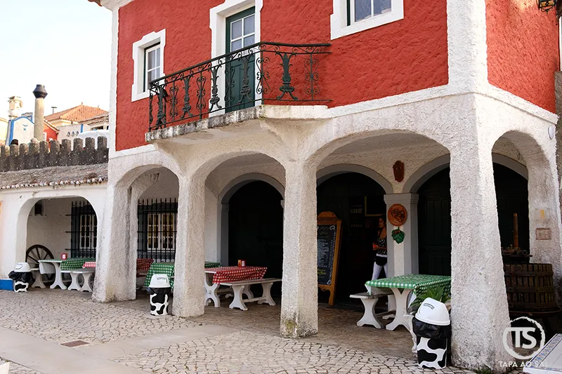 Restaurante com fachada vermelha e mesas exteriores na Aldeia José Franco em Mafra