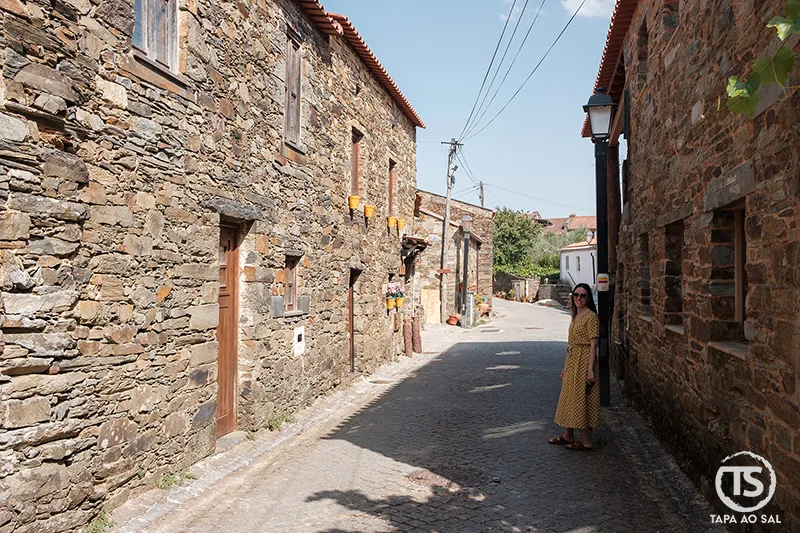 Rua de xisto na Aldeia da Figueira com casas tradicionais e visitante a caminhar
