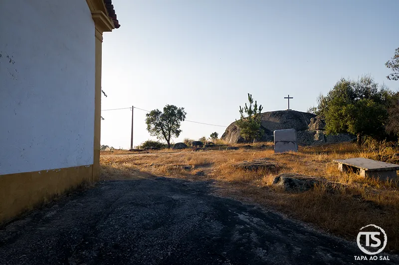 Caminho lateral da Capela de Nossa Senhora da Redonda em Alpalhão com penedo granítico coroado por cruz.