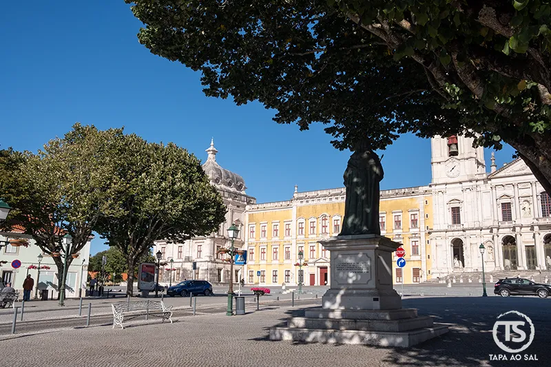 Mafra o que visitar: Terreiro D. João V e Palácio Nacional vistos entre árvores e estátua
