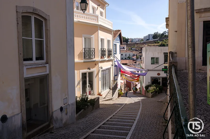Rua inclinada no centro de Monchique com casas coloridas e bandeiras festivas
