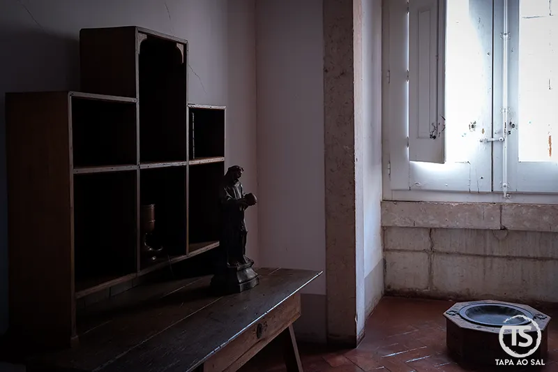 Cela simples do Convento de Mafra no Palácio Nacional com mobiliário austero e luz a entrar pela janela