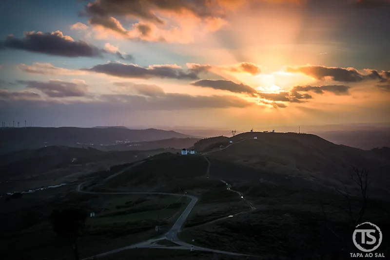 Estrada sinuosa entre colinas ao pôr do sol em Portugal, evocando alugar carro em Portugal para percorrer paisagens abertas