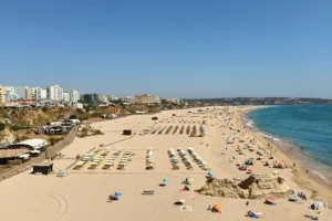 Praia da Rocha em Portimão vista panorâmica, areal extenso, mar azul e arribas urbanas, um dos principais locais a visitar em Portimão