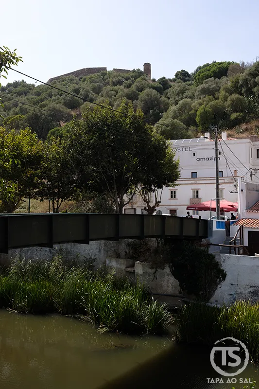 Things to do in Aljezur — bridge over the river with Castelo de Aljezur rising above the old town and green valley