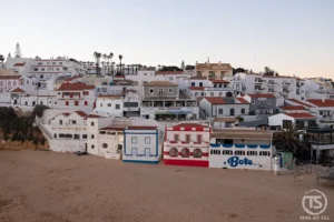 Praia do Carvoeiro com casas brancas sobre a areia ao entardecer, no guia Carvoeiro o que visitar