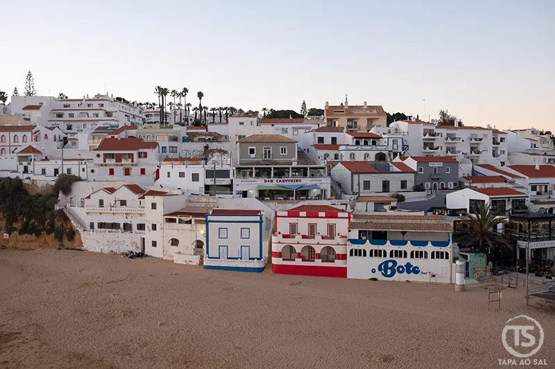 Praia do Carvoeiro com casas brancas sobre a areia ao entardecer, no guia Carvoeiro o que visitar