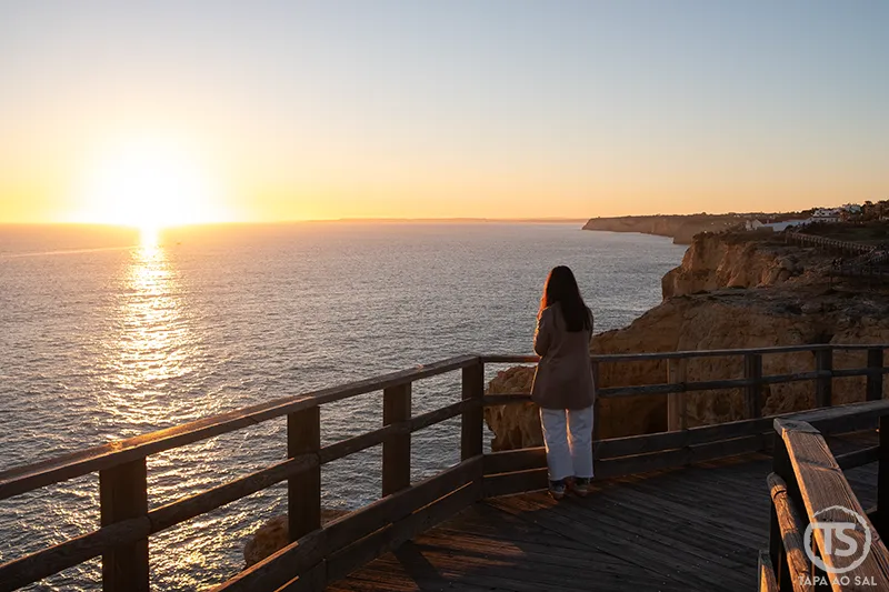 Pôr do sol no Algarve sobre falésias junto ao mar, num miradouro costeiro com vista ampla do litoral