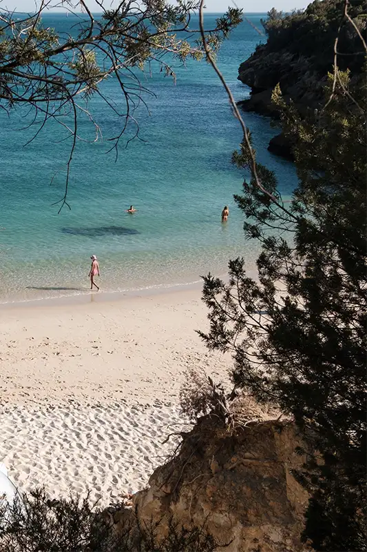 Praia em Portugal com areia clara e mar azul, representando guias de viagem sobre praias
