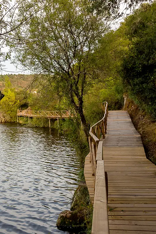 Passadiço de madeira junto a curso de água em Portugal, representando trilhos de caminhada