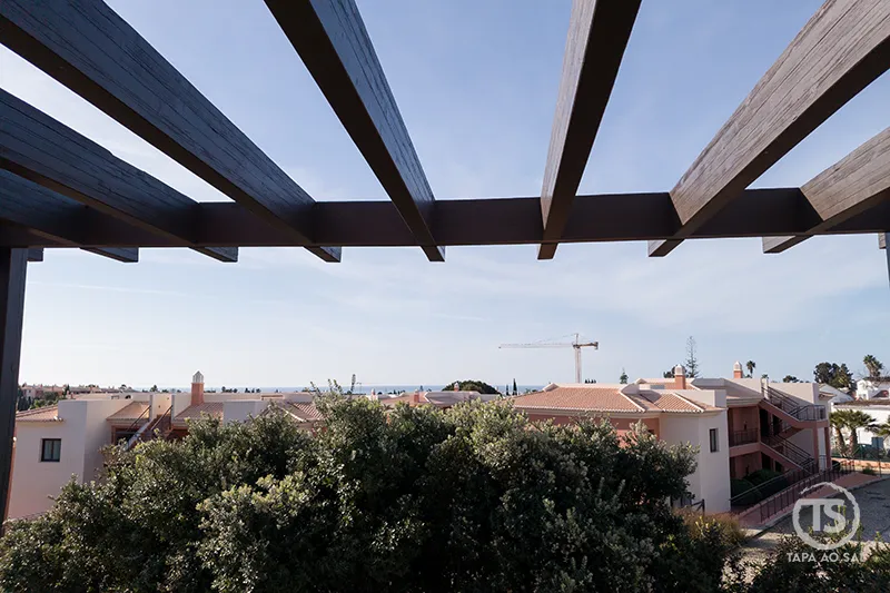 Vista do Monte Santo Resort Carvoeiro desde a varanda, com pérgula em madeira e edifícios do resort no Algarve ao fundo.