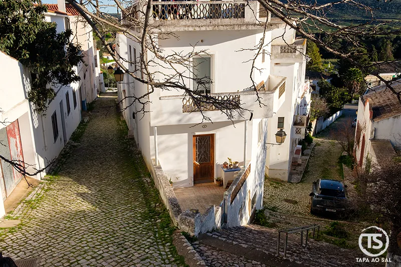 Alte o que visitar rua inclinada com casa branca e calçada tradicional