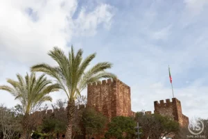 Castelo de Silves com muralhas em arenito vermelho e palmeiras junto às torres da fortaleza no Algarve