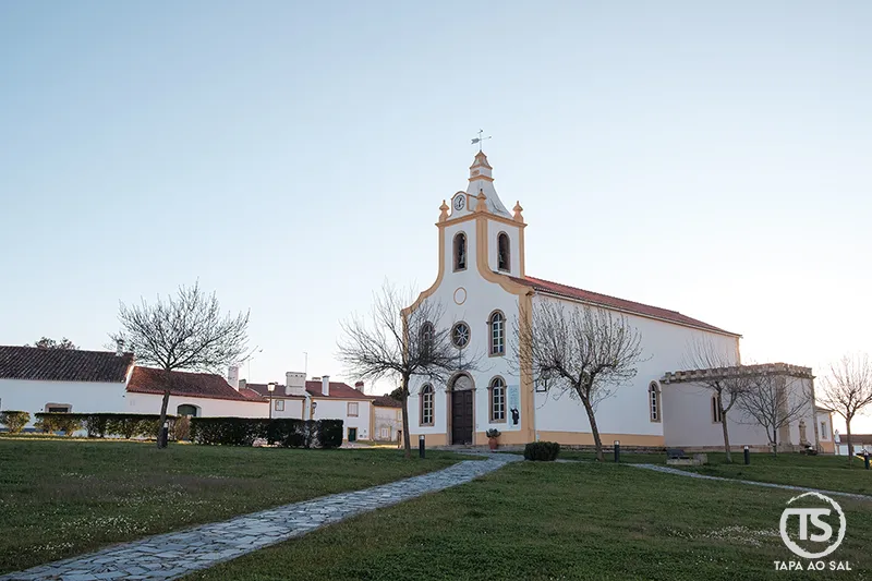 Igreja em Flor da Rosa no concelho do Crato, rodeada por relvado e arquitetura tradicional do Alto Alentejo