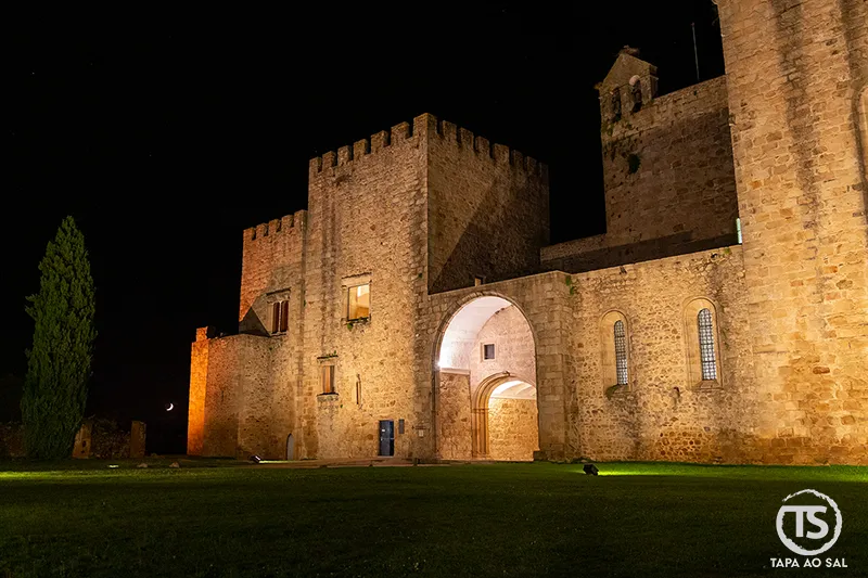 Mosteiro de Flor da Rosa iluminado à noite no Crato, com fachada em pedra e ambiente silencioso